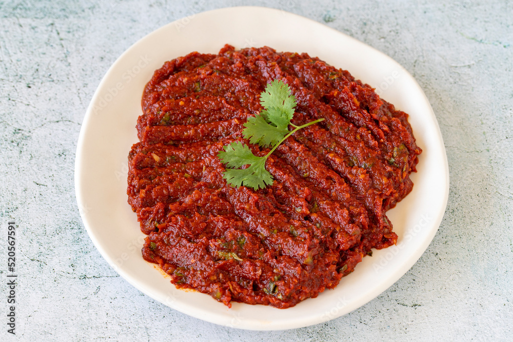 Adjika or chili paste. Hot chili peppers harissa sauce. Spicy paste appetizer on a stone background. close up Adjika or chili paste. Hot chili peppers harissa sauce. Spicy paste appetizer on a stone background. close up