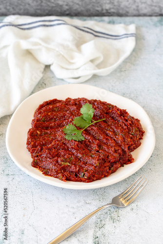 Adjika or chili paste. Hot chili peppers harissa sauce. Spicy paste appetizer on a stone background. close up