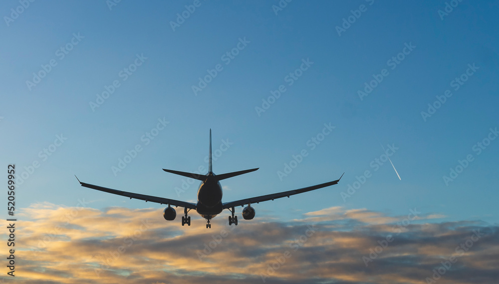 The silhouette of a passenger plane coming in for landing against the backdrop of the sunset sky. The silhouette of a passenger plane coming in for landing against the backdrop of the sunset sky.