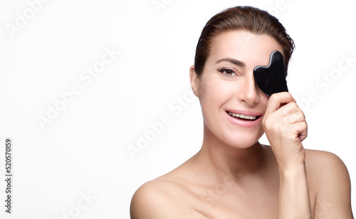 Happy healthy beautiful woman with a Gua sha lifting tool. Beauty and skin care concept