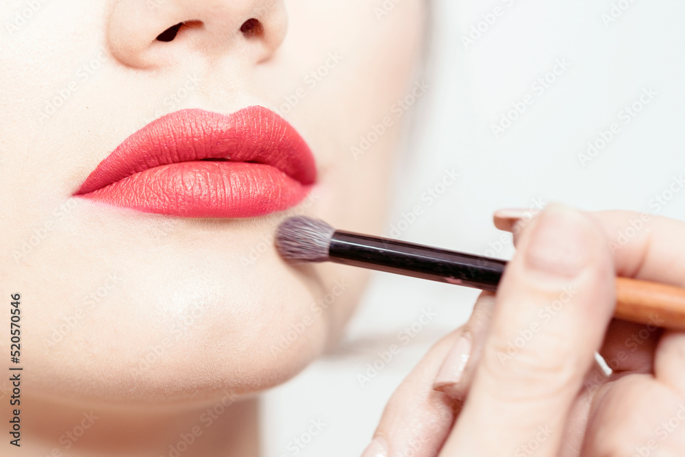 Makeup lips. Makeup artist hand adjusts makeup, final touches.