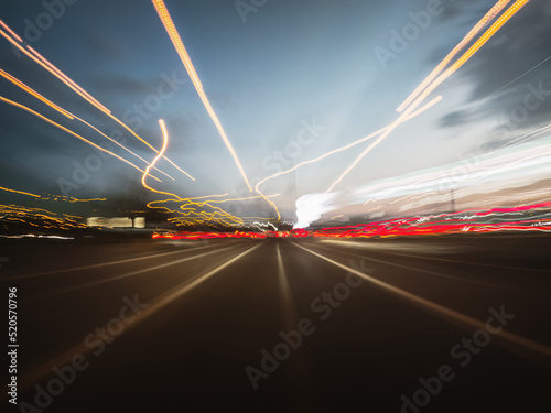 Beautiful shot of a car rush on the night road with colorful light trails, front view from the car window.