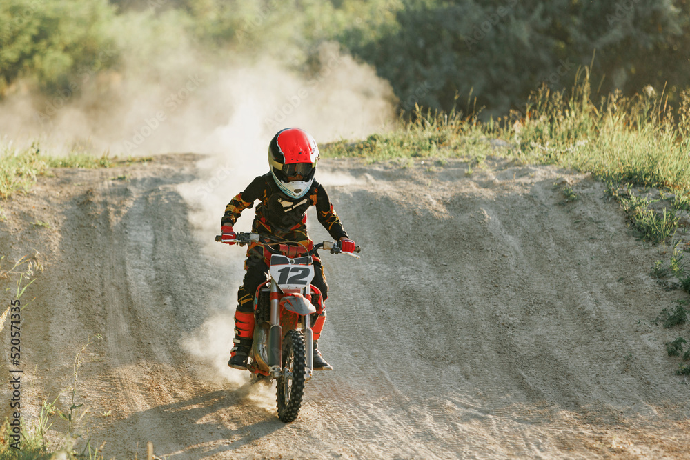 Live shot of junior sportsman, motorcyclist training on motorbike at hot summer day, outdoors. Motocross rider in action. Motocross sport, challenges