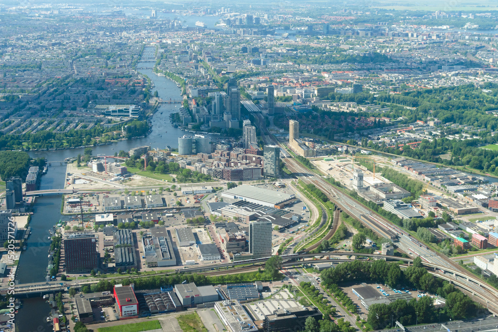 Aerial view from airplane of modern city with buildings, skyscrapers and highways between river. Amsterdam, Holland 