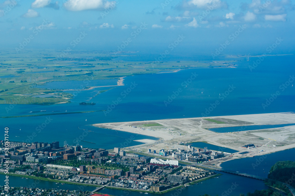 Aerial view from airplane of modern city with buildings, skyscrapers and highways close to sea with beach. Amsterdam, Holland 