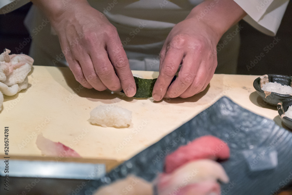 Chef's hands cooking sushi rolls in the kitchen, close up, traditional Japanese food.