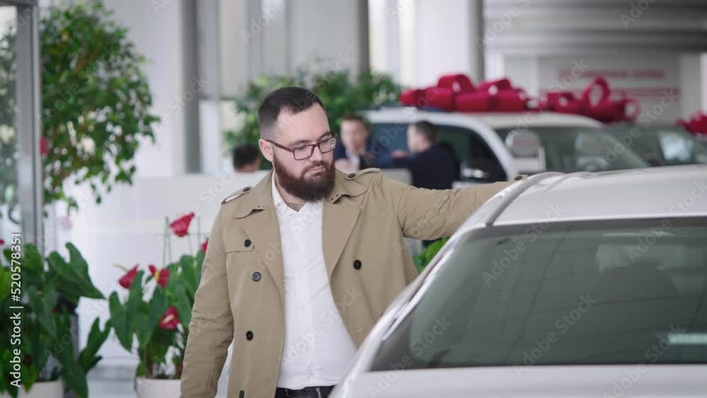 Serious adult man buys a new car. The choice of car for everyday affairs. Serious adult man buys a new car. The choice of car for everyday affairs.