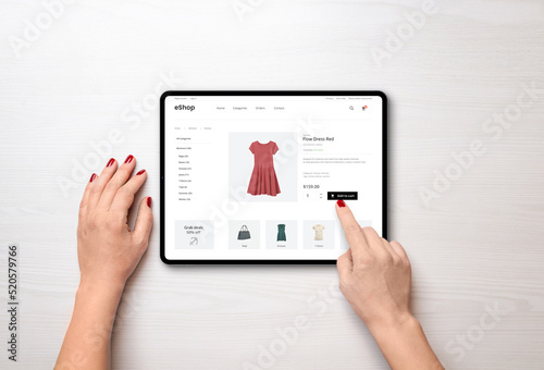 Online shopping with a tablet. Red women's dress on the e-commerce web page