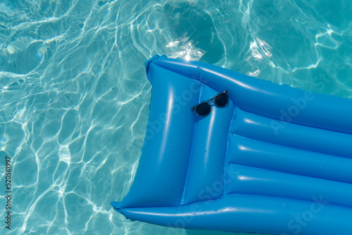 Sunglasses on a blue swimming pool float. Summer holiday background © ink drop