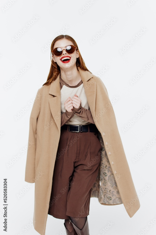 Obraz premium Cheerful laughing cute redhead young woman posing in glasses coat on a white background in the studio. Catalog photography