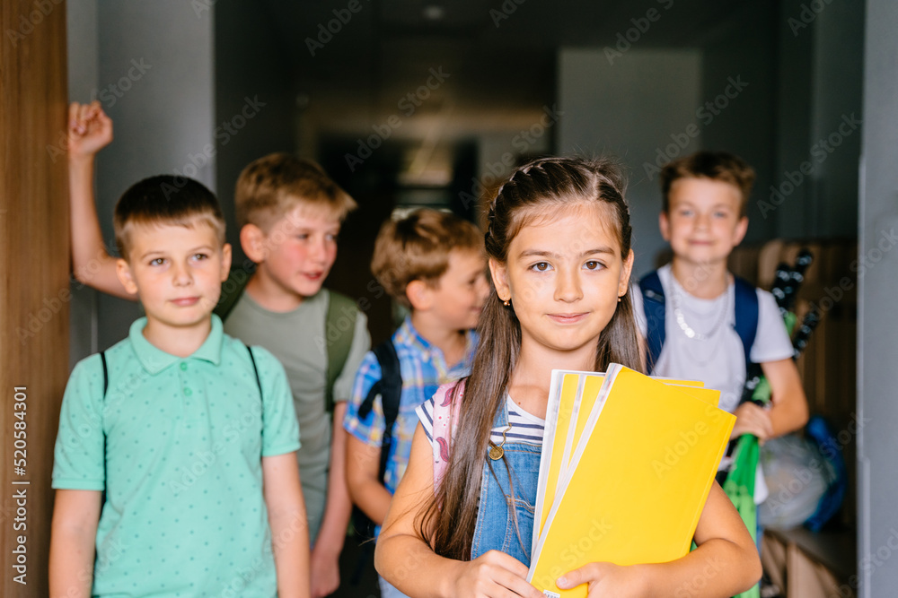 Portrait of smart little hispanic girl holding yellow notebooks among classmates during break ptivat school. Portrait of smart little hispanic girl holding yellow notebooks among classmates during break ptivat school.