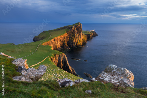 Golden evening sunlight casting on cliffs of Neist Point Lighthouse on the Isle of Skye, Scotland, UK. photo