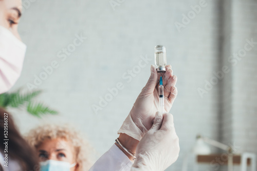 Close-up of hand in gloves extracting fluid to syringe for injection. Coronavirus vaccination. Healthcare, medicine, pharmacy and vaccination concepts