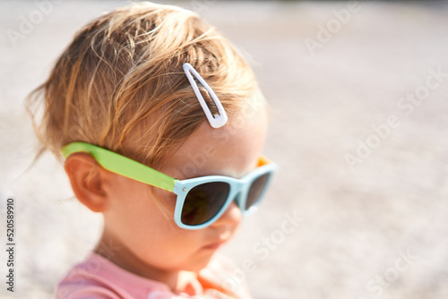 Little girl in sunglasses with a hairpin on her head. Portrait photo