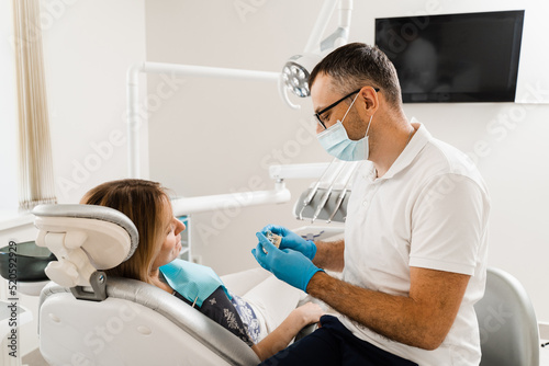 Dental prosthetics and implants. Doctor dentist shows artificial plastic jaw with dental implants. Dental prosthetics consultation with dentist for patient woman in dentistry.
