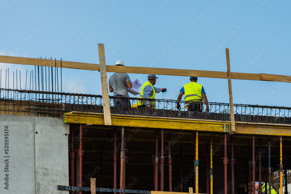 Three workers and a contractor on top of a construction site along with an engineer pointing to something