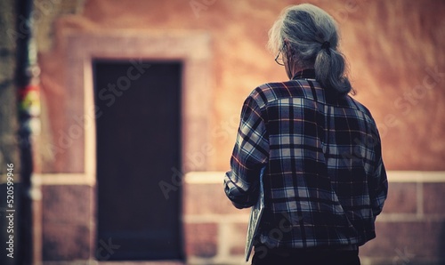 Back view of a senior male with long gray hair and a plaid shirt