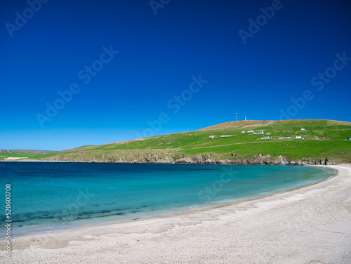 The white sand and turquoise water of Spiggie Beach  Scousburgh Beach  in southern Shetland  UK. Taken on a sunny day with a clear blue sky.
