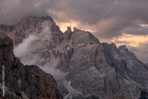 Sunset light above Tofane with some low clouds hanging between rocks, Dolomites, Italy photo