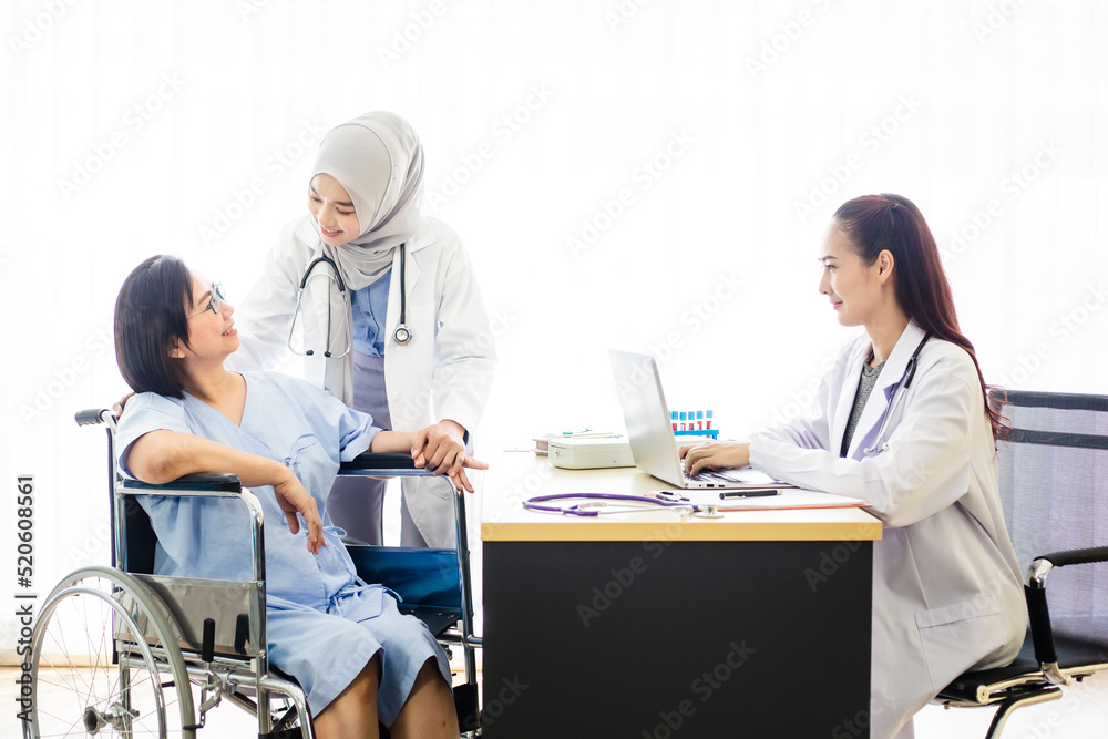 Fototapeta premium Senior patient woman sitting on wheelchair and having consultation with Muslim and Asian doctor in hospital. Healthcare and assistance concept.
