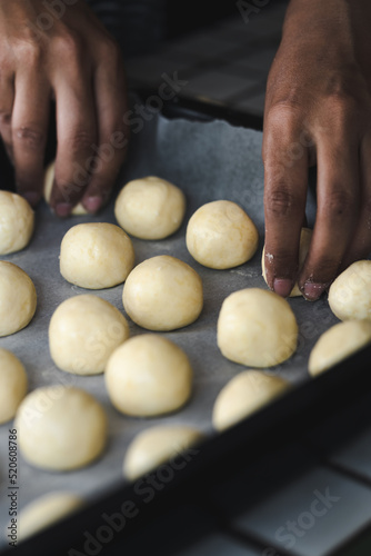 Woman placing rolls of Chipa, a traditional paraguayan bread, on a baking pan