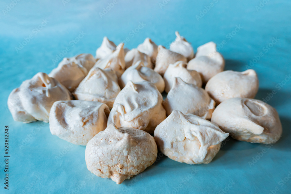 Homemade french milk-colored meringues on blue paper Homemade french milk-colored meringues on blue paper