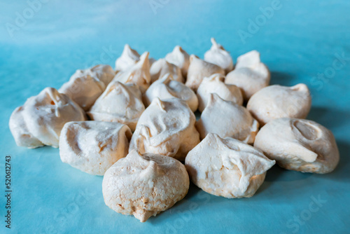 Homemade french milk-colored meringues on blue paper