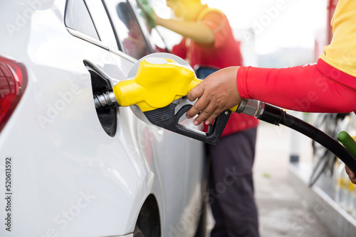 Transportation and ownership concept - woman pumping gasoline fuel in car at gas station during Russia-Ukraine war that oil or gasohol price high.