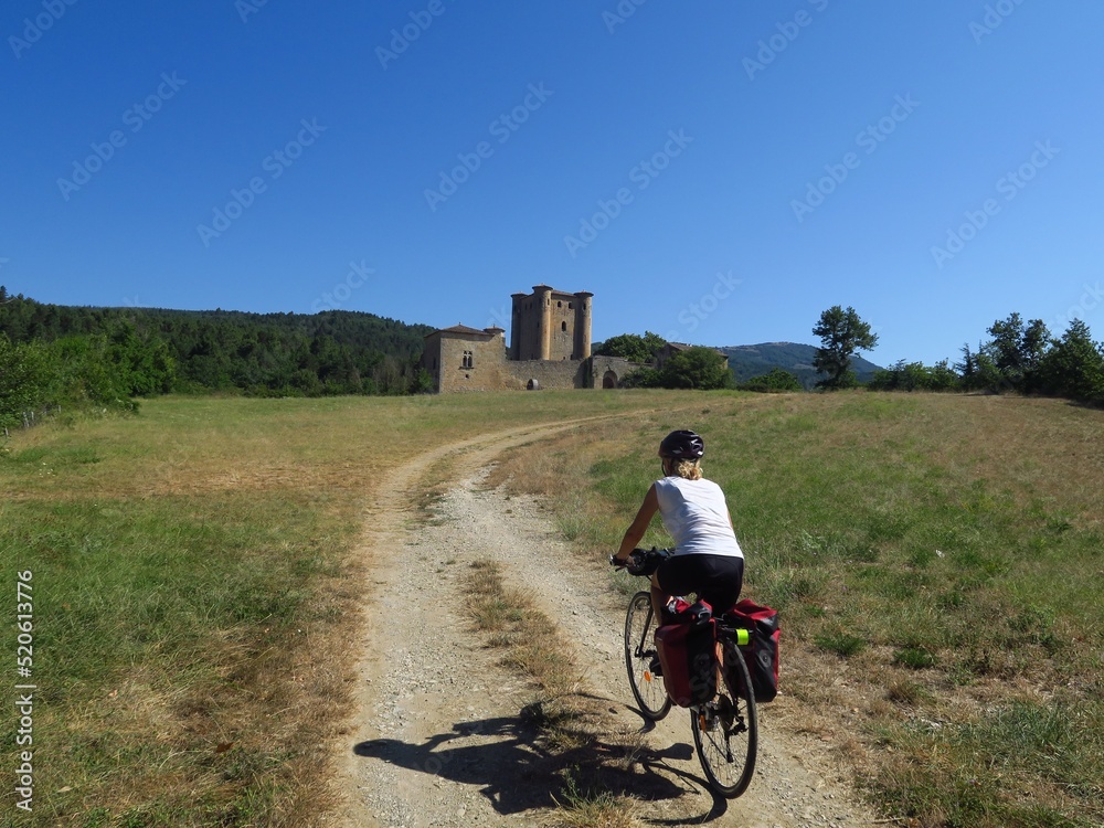 Obraz premium jeune femme à Vélo montant vers un château médiéval d'Arques dans l'Aude sud de France