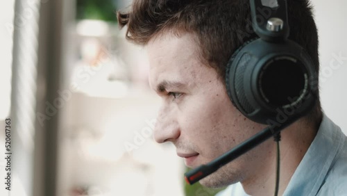Close Up Portrait of a Joyful Technical Customer Support Specialist Talking on a Headset while Working on a Computer in a Call Center Control Room