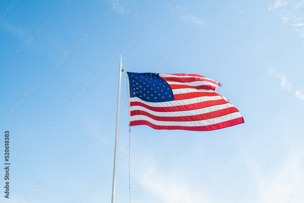 Fototapeta premium America flag waving in the wind over a bright blue and sunny sky background
