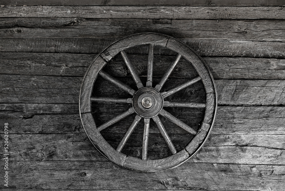 Old wooden wheel on a wooden wall.