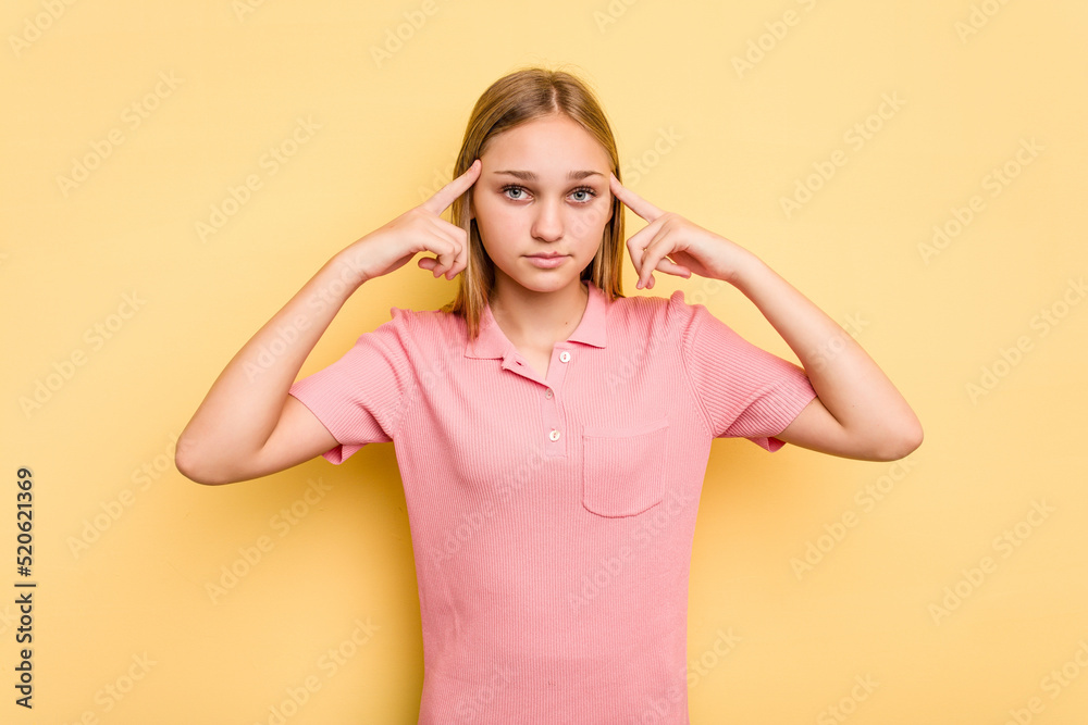 Young caucasian girl isolated on yellow background focused on a task, keeping forefingers pointing head. Young caucasian girl isolated on yellow background focused on a task, keeping forefingers pointing head.