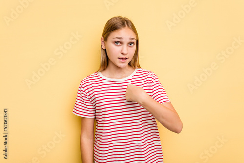 Young caucasian girl isolated on yellow background surprised pointing with finger, smiling broadly.