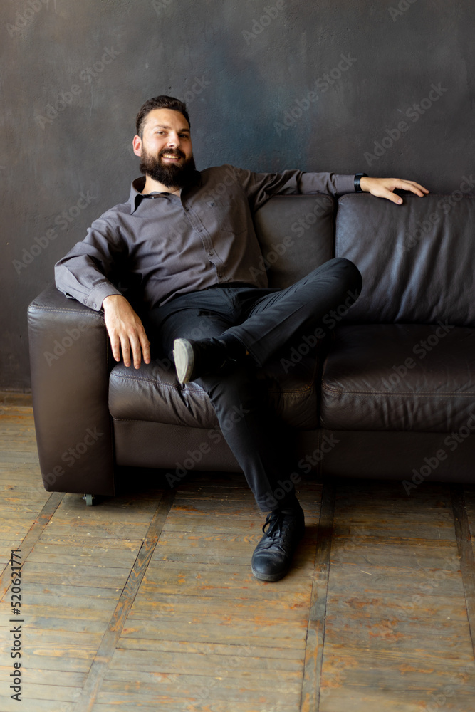 A man with a black beard is sitting on a leather sofa. Businessman A man with a black beard is sitting on a leather sofa. Businessman