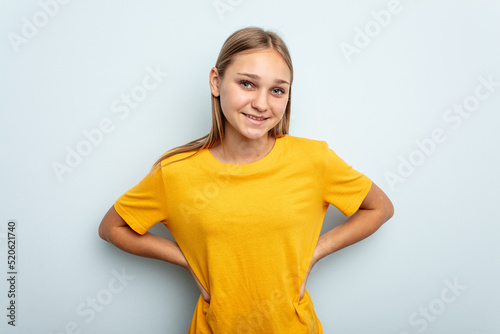 Young caucasian girl isolated on blue background confident keeping hands on hips.