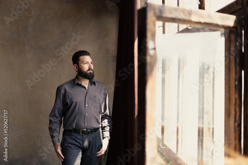 A young bearded man in a suit looks out the window