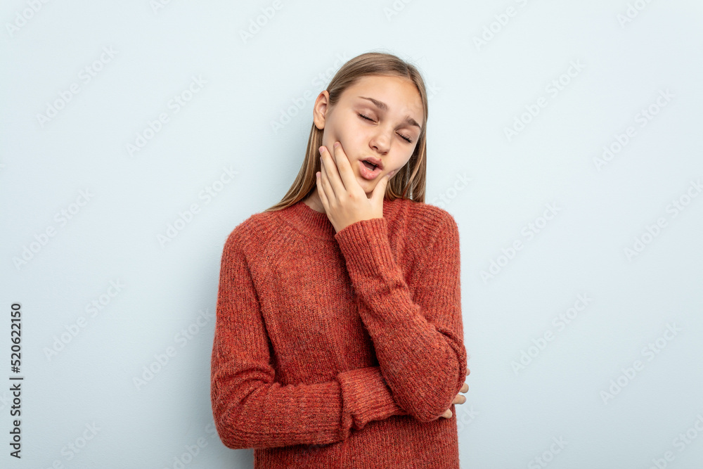 Young caucasian girl isolated on blue background having a strong teeth pain, molar ache. Young caucasian girl isolated on blue background having a strong teeth pain, molar ache.
