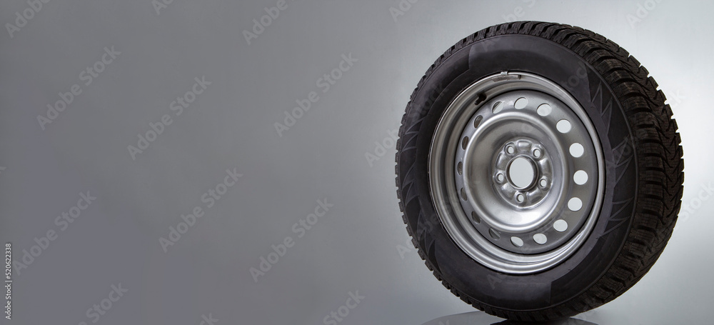 Obraz premium Car wheel and winter studded tire on white