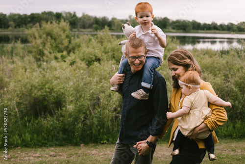 Mother, father, son and daughter walk along lakeside as a family