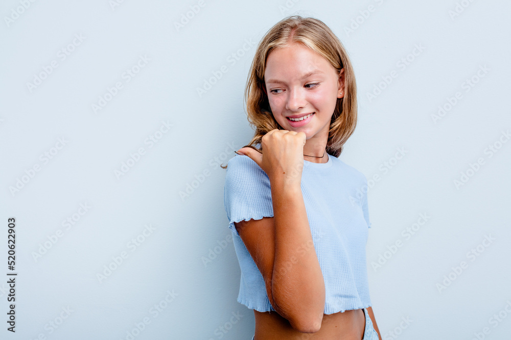 Caucasian teen girl isolated on blue background points with thumb finger away, laughing and carefree. Caucasian teen girl isolated on blue background points with thumb finger away, laughing and carefree.
