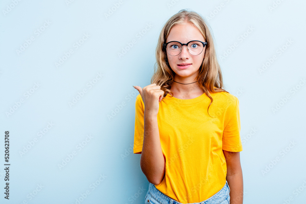 Caucasian teen girl isolated on blue background shocked pointing with index fingers to a copy space. Caucasian teen girl isolated on blue background shocked pointing with index fingers to a copy space.