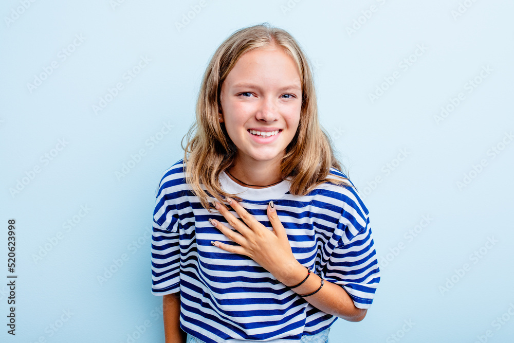 Caucasian teen girl isolated on blue background laughs out loudly keeping hand on chest. Caucasian teen girl isolated on blue background laughs out loudly keeping hand on chest.