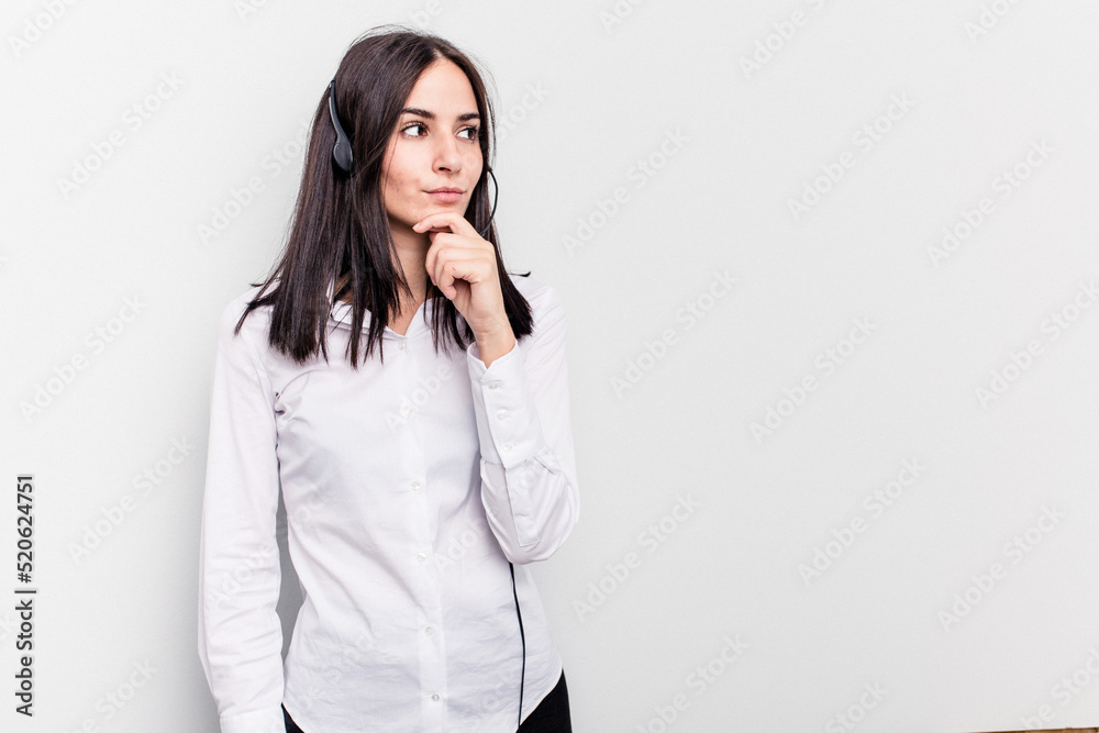 Telemarketer caucasian woman working with a headset isolated on white background looking sideways with doubtful and skeptical expression. Telemarketer caucasian woman working with a headset isolated on white background looking sideways with doubtful and skeptical expression.