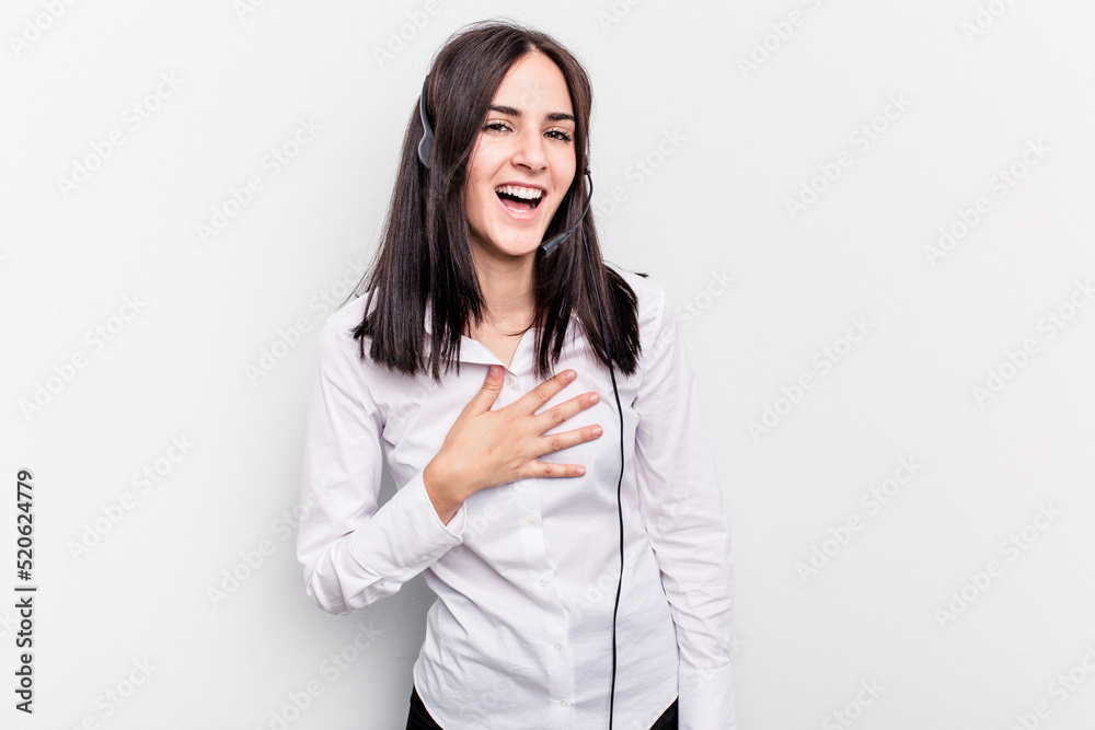 Telemarketer caucasian woman working with a headset isolated on white background laughs out loudly keeping hand on chest. Telemarketer caucasian woman working with a headset isolated on white background laughs out loudly keeping hand on chest.