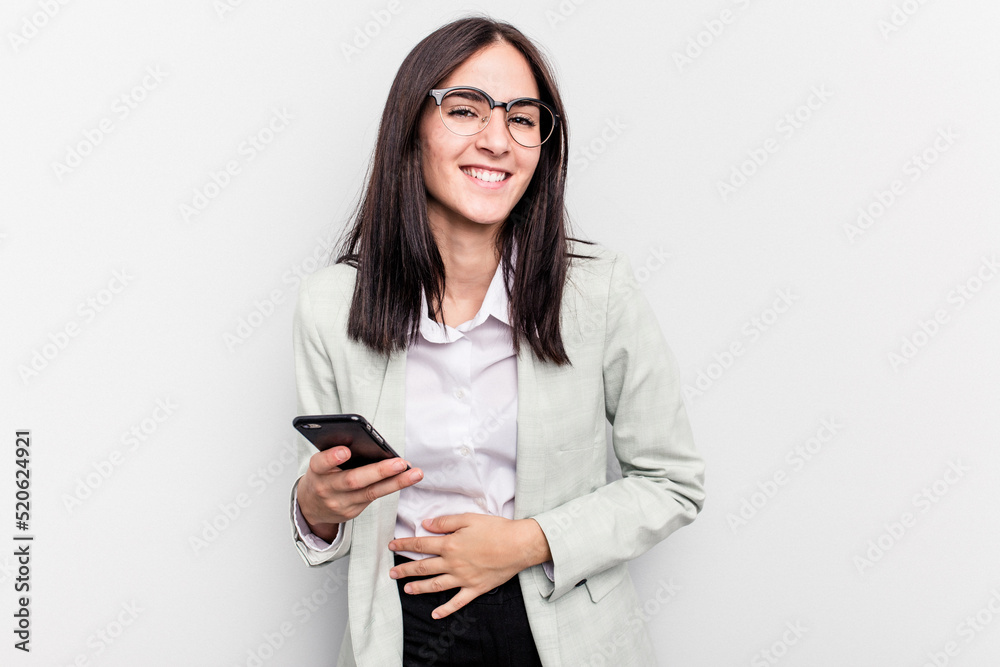 Young business caucasian woman holding mobile phone isolated on white background laughing and having fun. Young business caucasian woman holding mobile phone isolated on white background laughing and having fun.