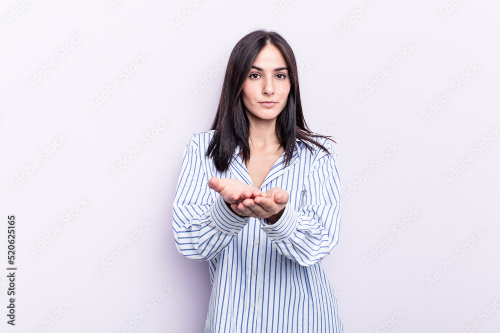 Young caucasian woman isolated on pink background holding something with palms, offering to camera. Young caucasian woman isolated on pink background holding something with palms, offering to camera.