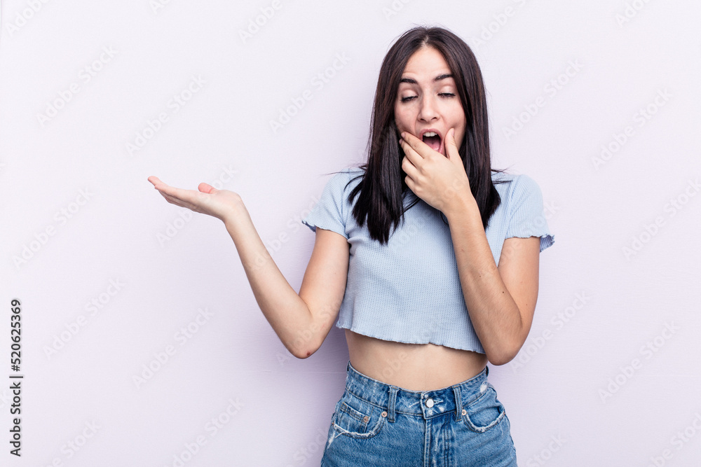Young caucasian woman isolated on pink background holds copy space on a palm, keep hand over cheek. Amazed and delighted. Young caucasian woman isolated on pink background holds copy space on a palm, keep hand over cheek. Amazed and delighted.