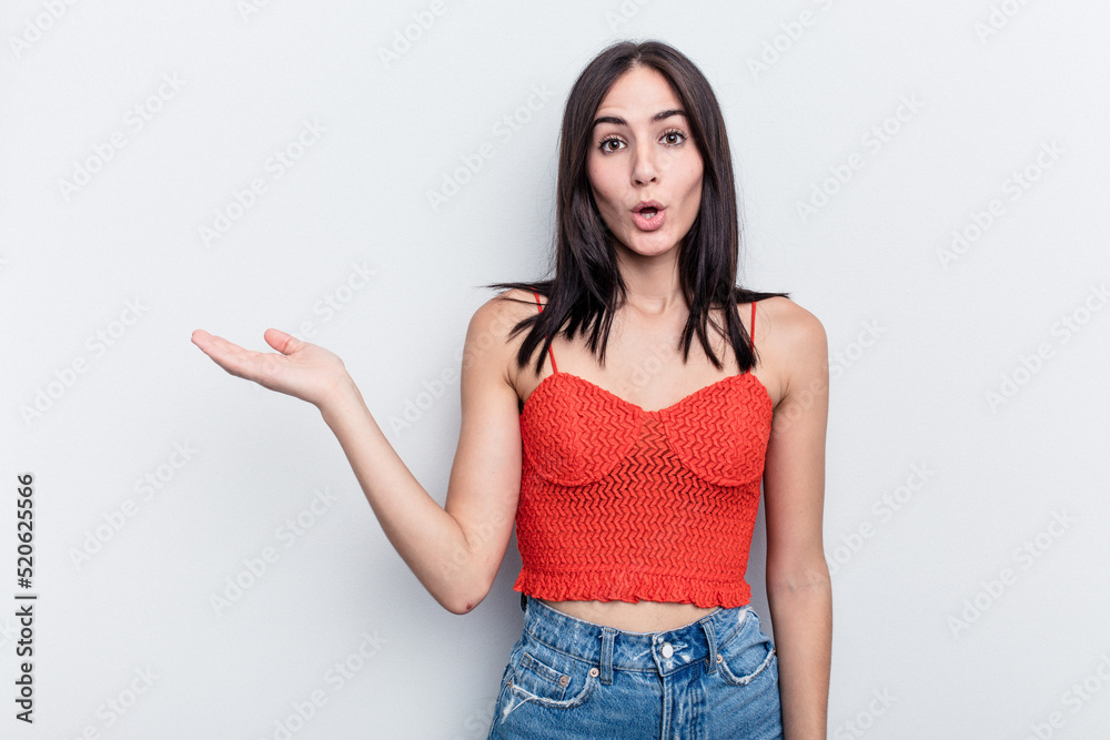 Young caucasian woman isolated on white background impressed holding copy space on palm. Young caucasian woman isolated on white background impressed holding copy space on palm.