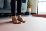 Legs of little girl in sportswear doing fitness exercises at home on pink mat. 